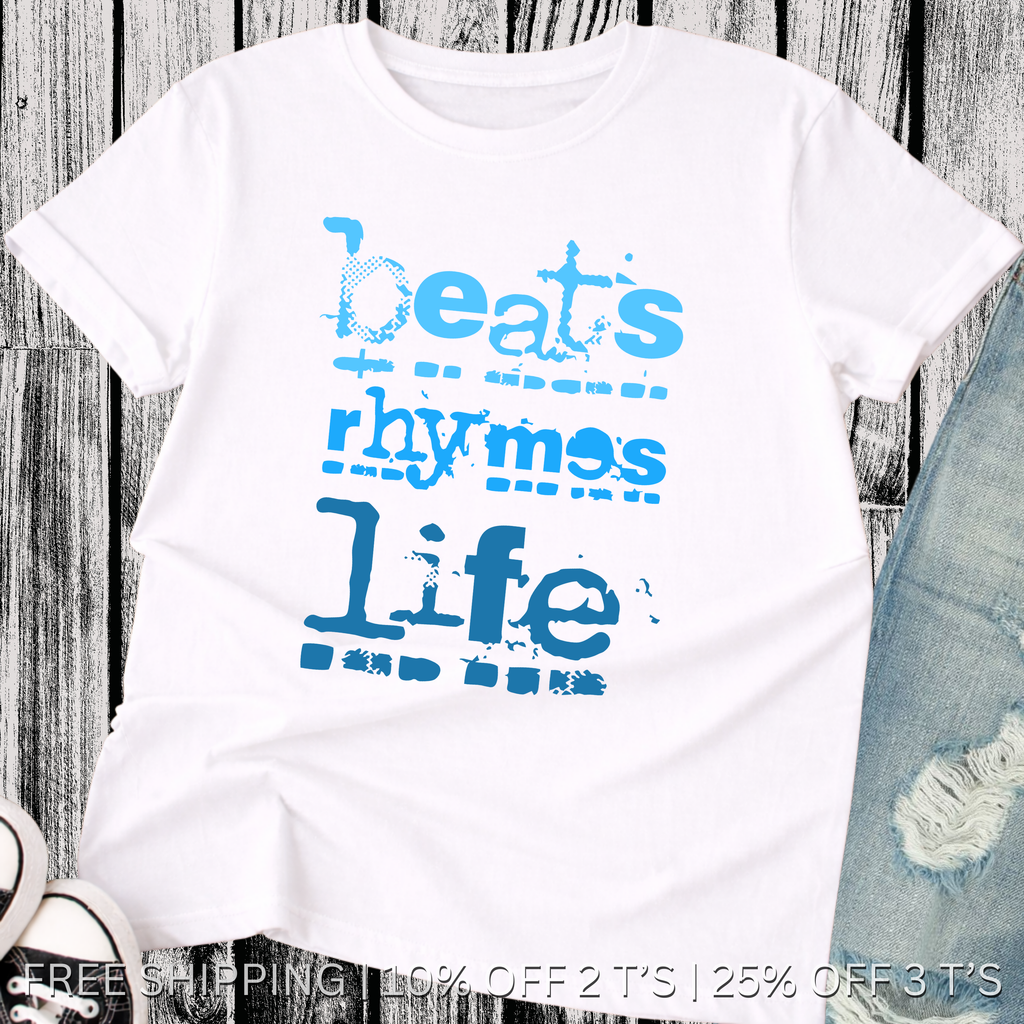 White t-shirt with blue text 'beats rhymes life' on a wooden surface.