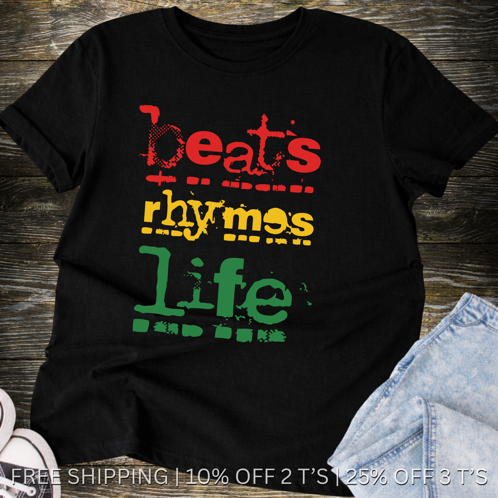 Black t-shirt with 'Beats Rhymes Life' text in red, yellow, and green on a wooden surface.